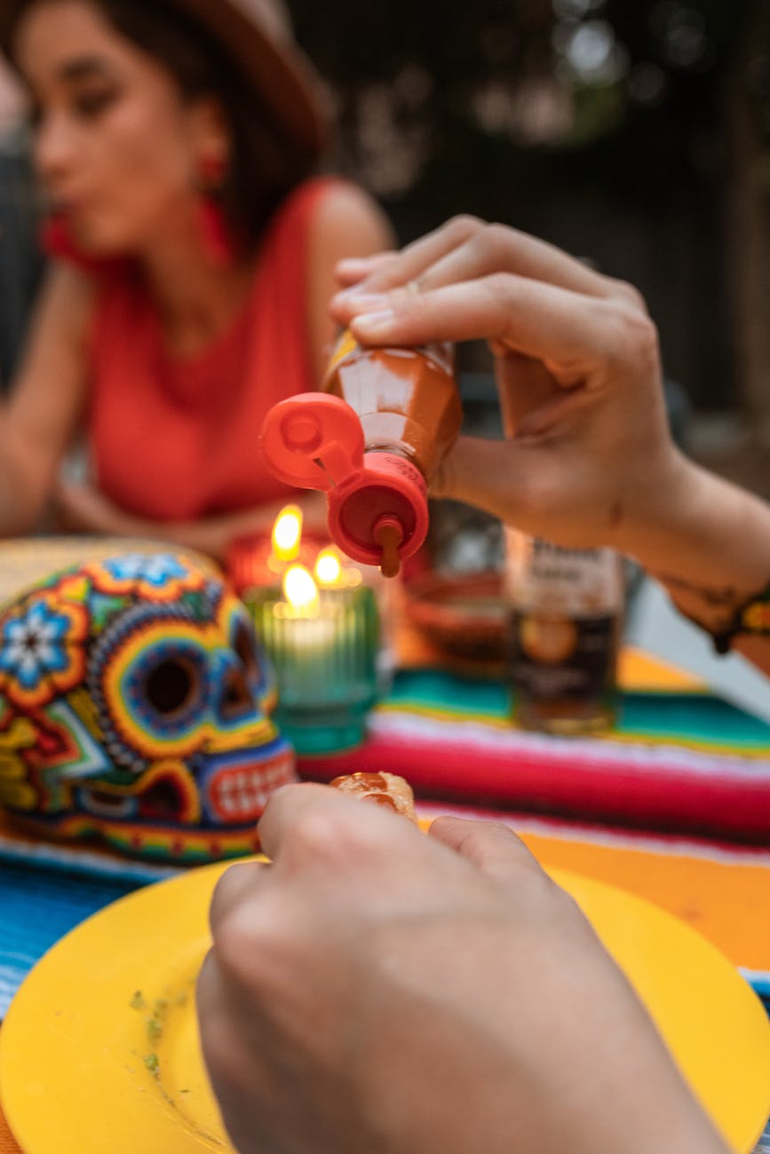 photo of a person putting hot sauce on food